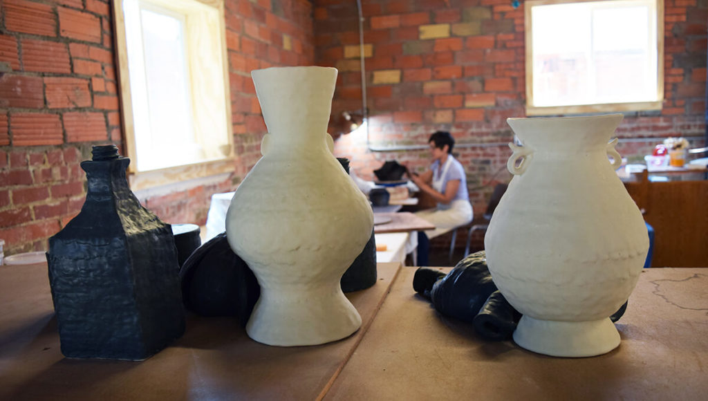Kelly O'Briant working in the Summer Studio with vases in the foreground