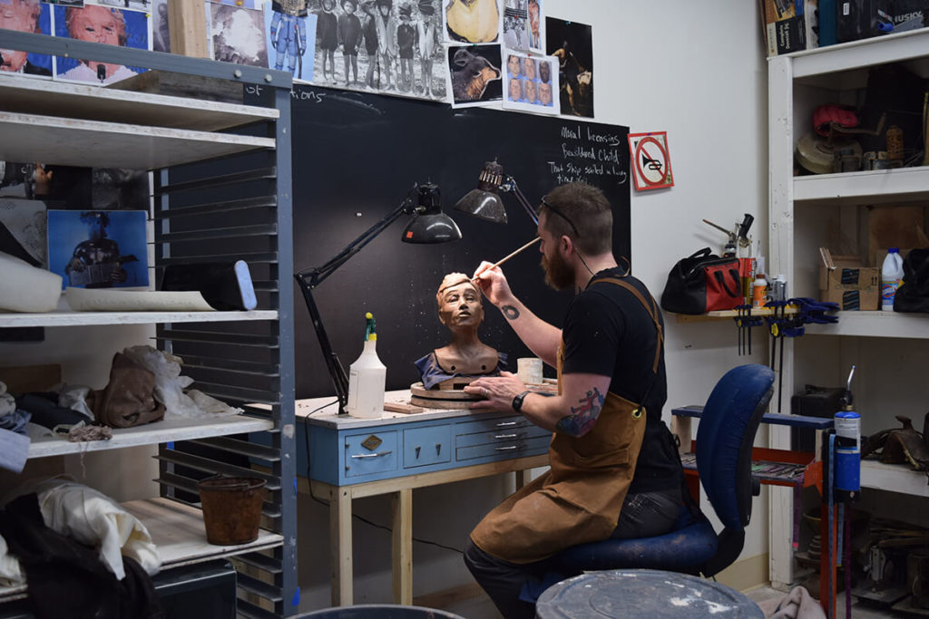 Richard W James working in Facilities studio with door on sculpture of head