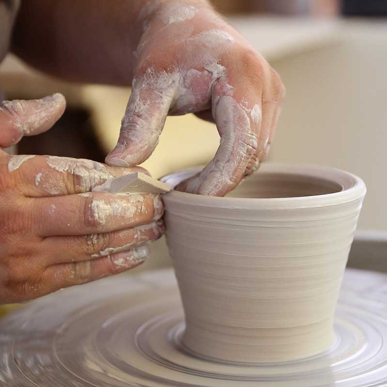 Hands working with clay on a pottery wheel